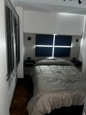 a bedroom with a large bed with a blue headboard at TREJO APART, A 40MTS DEL PATIO OLMOS, PLANTA BAJA in Cordoba