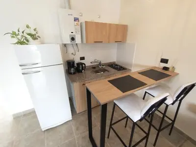 a kitchen with a white refrigerator and a table and chairs at Apart Deluxe in Mina Clavero
