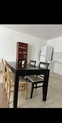 a black dining room table with chairs and a refrigerator at Depto por día in Río Cuarto