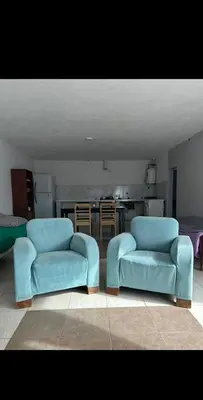 two blue chairs in a living room with a kitchen at Depto por día in Río Cuarto