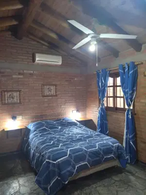 a bedroom with a blue bed and a brick wall at Suites de Montaña Despertar del Gallo in Villa Cura Brochero