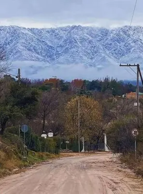 a dirt road with a snow covered mountain in the background at Suites de Montaña Despertar del Gallo in Villa Cura Brochero