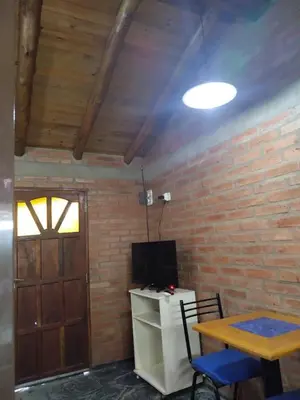 a room with a table and a tv and a brick wall at Suites de Montaña Despertar del Gallo in Villa Cura Brochero