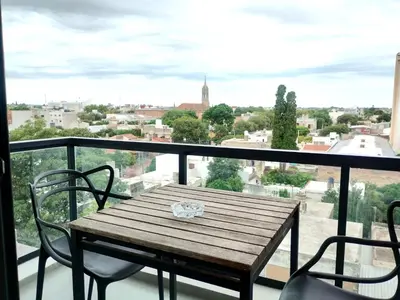 a wooden table and chairs on a balcony with a view at Depto 1 dormitorio totalmente equipado in Cordoba