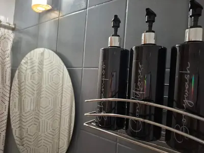 a bathroom with three black bottles and a mirror at Apartamento Nueva Cordoba in Cordoba