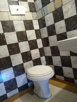 a bathroom with a toilet and a black and white tiled wall at Shakespeare 176 Ph3 in Villa Carlos Paz