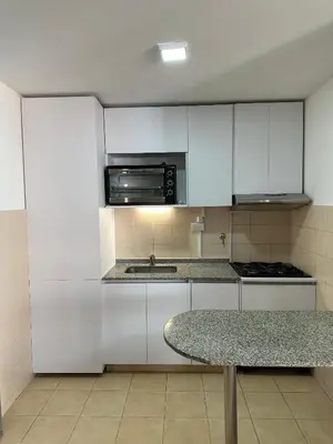 a kitchen with white cabinets and a sink and a table at Departamento Remodelado en Nva in Cordoba