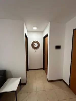a hallway with white walls and a table and a door at Departamento Remodelado en Nva in Cordoba