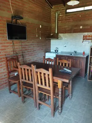 a kitchen with a wooden table and chairs and a television at El descanso in Villa Ciudad Parque