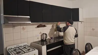 a man standing in a kitchen looking up at the cabinets at pepesapart in Cordoba