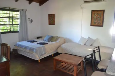 a bedroom with two beds and a table and a window at Depto Granja de Funes in Cordoba
