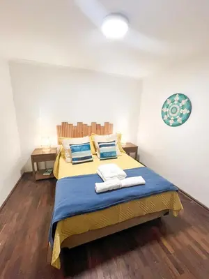 a bedroom with a yellow bed with blue sheets and blue pillows at Departamento en NUEVA CÓRDOBA a cuadras de Plaza España y del consulado español in Cordoba