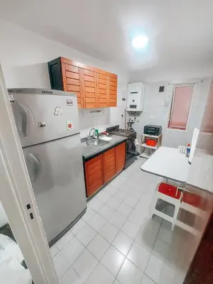 a kitchen with a stainless steel refrigerator and wooden cabinets at Departamento en NUEVA CÓRDOBA a cuadras de Plaza España y del consulado español in Cordoba