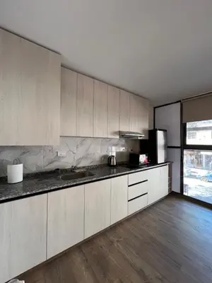a kitchen with white cabinets and a wooden floor at Departamento Carlos Paz in Villa Carlos Paz