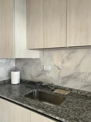 a kitchen counter with a sink and wooden cabinets at Departamento Carlos Paz in Villa Carlos Paz