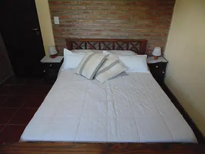 a bed with white sheets and pillows in a bedroom at Cabañas los amigos Chañar in Potrero de Garay