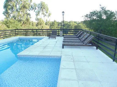 a swimming pool with two benches next to a fence at Cabañas los amigos Chañar in Potrero de Garay