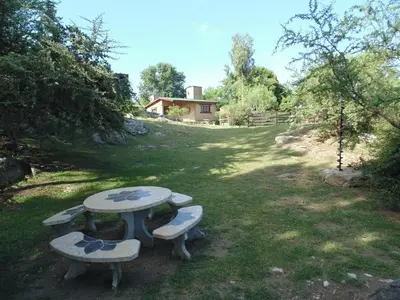 a picnic table with three benches in a field at Cabañas los amigos Chañar in Potrero de Garay