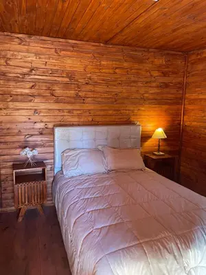 a bed in a room with a wooden wall at Kapo TEAM , la calandria in Villa Amancay