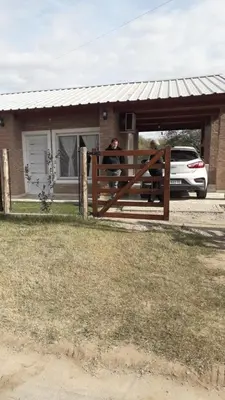 a man standing behind a fence in front of a house at Cabaña La Luna in San Javier
