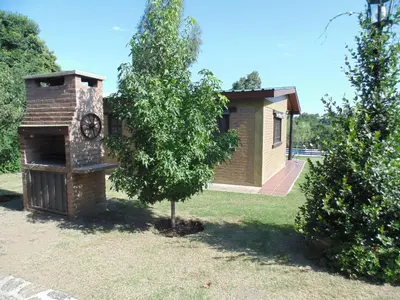 a building with a clock on it next to a tree at Cabañas los amigos Tala in Potrero de Garay