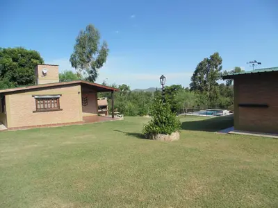 a building with a yard with a tree in the grass at Cabañas los amigos Tala in Potrero de Garay