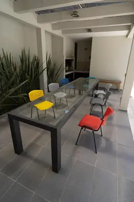 a large glass table with colorful chairs in a room at Complejo Solares in Alta Gracia