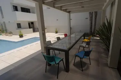 a glass table and chairs in a patio with a pool at Complejo Solares in Alta Gracia