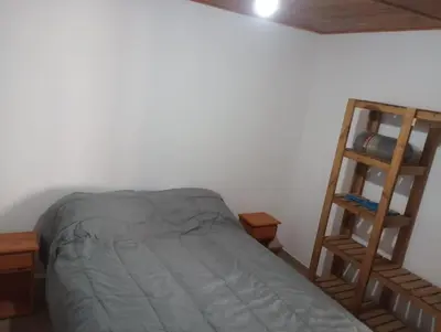 a bedroom with a bed and a wooden ladder at Los 3 soles in Villa Ciudad Parque