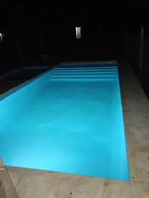a large blue swimming pool at night at Los 3 soles in Villa Ciudad Parque