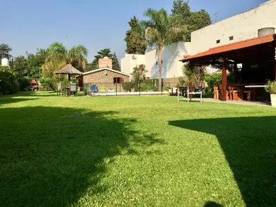 a large field of grass with a building in the background at Cabañas Lauquen Villa Carlos Paz in Villa Carlos Paz