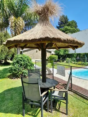 a table and a chair under a straw umbrella at Cabañas Lauquen Villa Carlos Paz in Villa Carlos Paz