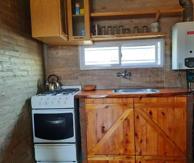 a kitchen with a stove and a sink at Cabaña Emmanuel in Santa Rosa de Calamuchita
