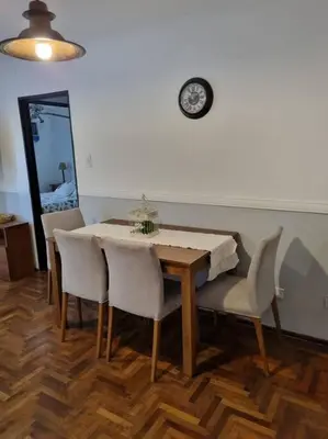 a dining room table with chairs and a clock on the wall at Hermoso y cómodo Dpto en el centro in Cordoba