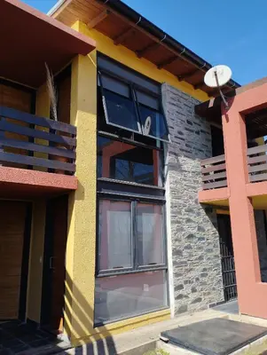 a house with black windows and a balcony at Paraíso Serrano 12 in Villa Ciudad Parque
