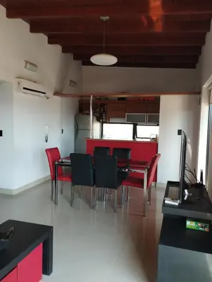 a dining room with red chairs and a table at Paraíso Serrano 12 in Villa Ciudad Parque
