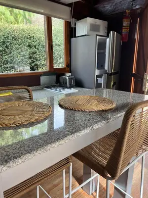 a kitchen with a counter with chairs and a refrigerator at Willert Cabañas Cumbrecita in La Cumbrecita