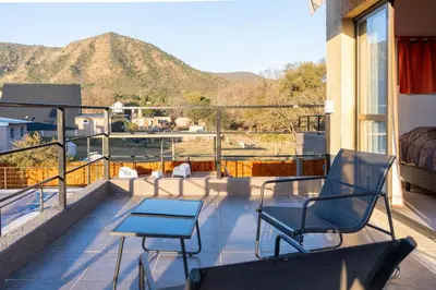 a balcony with two chairs and a table and a mountain at Cabañas Miraluna in Villa General Belgrano