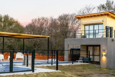 a house with a patio and a building at Cabañas Miraluna in Villa General Belgrano