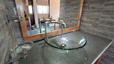 a bathroom with a glass sink and a mirror at Cabañas Aires de Montaña in La Estancia