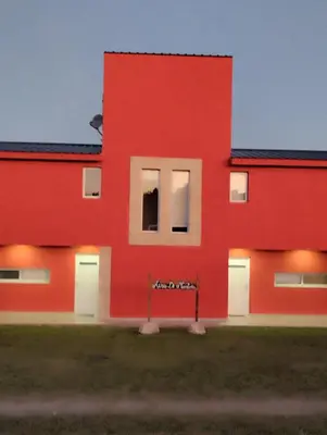 a red building with white doors and windows at Cabañas Aires de Montaña in La Estancia