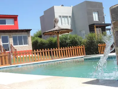 a swimming pool with a fountain in front of a house at Cabañas Aires de Montaña in La Estancia
