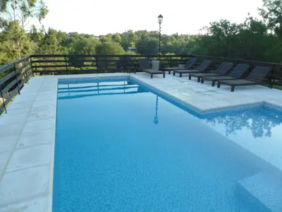 a swimming pool with benches and blue water at Cabañas los amigos Pino in Potrero de Garay