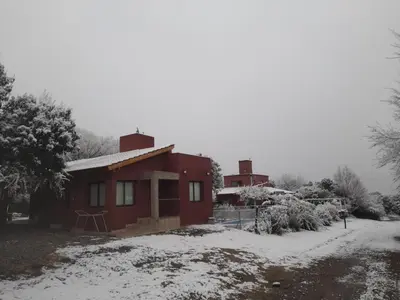 a small red house with snow on the ground at Luz del Rincón in Merlo