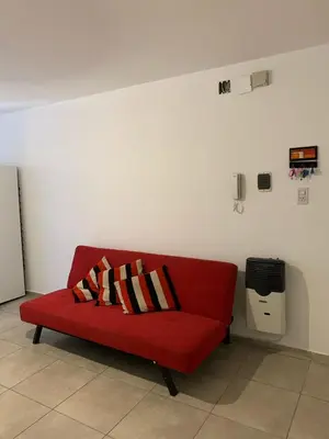 a red couch with two pillows on it in a room at Hermoso departamento amoblado ubicado en pleno Nueva Córdoba in Cordoba