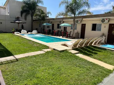 a swimming pool in a yard with chairs next to a house at Complejo Roccatini in Villa Carlos Paz