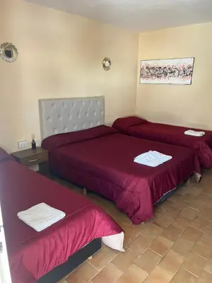 two beds in a room with red sheets at Complejo Roccatini in Villa Carlos Paz