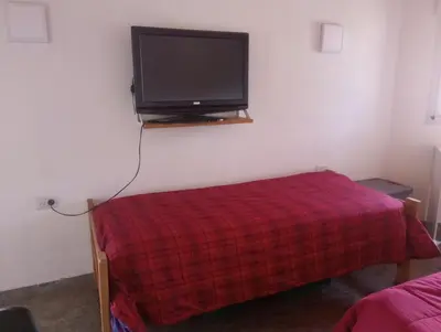 a room with a tv and a bed with a red blanket at Magnolias in Villa General Belgrano
