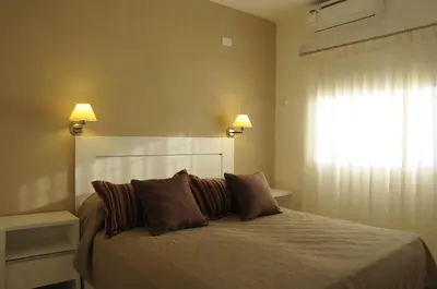 a bedroom with a bed with two pillows and a window at Lom Suites in Merlo