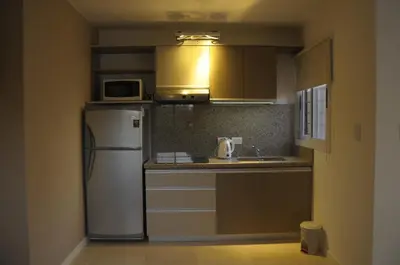 a kitchen with a refrigerator and a microwave at Lom Suites in Merlo